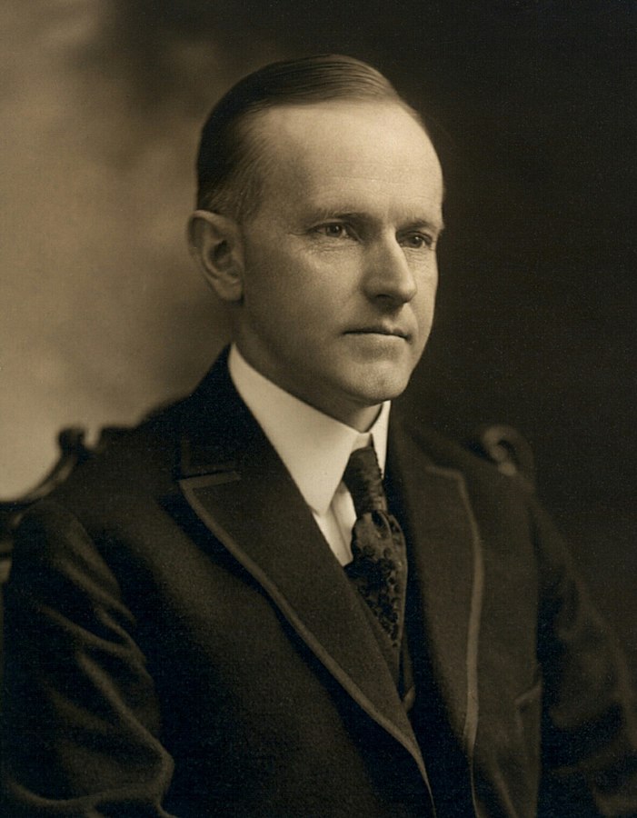 701px-Calvin_Coolidge,_bw_head_and_shoulders_photo_portrait_seated,_1919